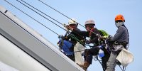 3 personnes en hauteur sur un bâtiment équipés d'un harnais de sécurité